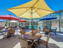 Patio tables with colorful table umbrellas next to the indoor swimming pool