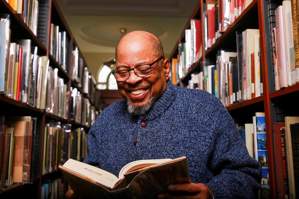 Judge Rudolph "Barry" Loncke sitting in a library reading a book and smiling.
