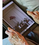 A resident holding their iPad, looking at photos.